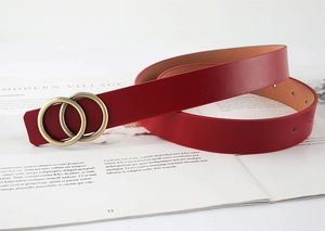 Détail de la ceinture en cuir rouge avec boucle dorée à double anneau et trous
