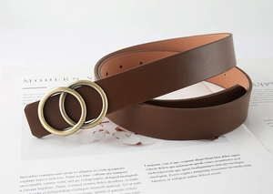 Détail d'une ceinture en cuir marron foncé avec une boucle classique à double anneau doré