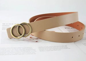 Détail de la ceinture en cuir kaki avec boucle double anneau en bronze sur un magazine