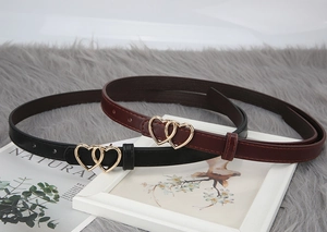 Detail of slim black and wine red belts with gold interlocking double heart buckles