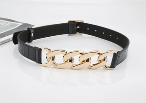 Détail de la ceinture noire motif crocodile avec de gros maillons de chaîne dorés polis