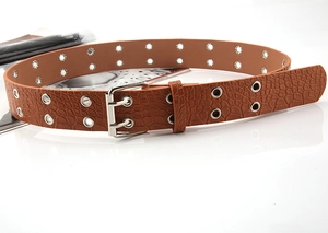 Detail of brown crocodile pattern belt with double silver eyelets and metal buckle