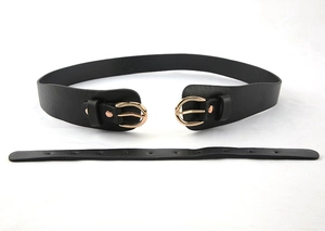 Détail d'une large ceinture en cuir noir avec doubles boucles en D dorées pour manteaux