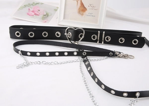 Detail of punk style black leather belt featuring silver heart buckle and metal chains