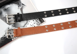 Detail of stone-patterned leather belt with double rows of metal eyelets and silver buckle