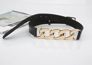 Détail de la ceinture noire en simili cuir crocodile avec grosse chaîne dorée