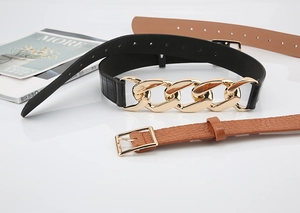 Détail d'une ceinture texture crocodile avec chaîne dorée et cuir marron au motif litchi