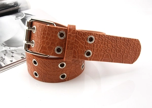 Detail of brown croc-embossed leather belt featuring silver double-prong buckle and metal eyelets