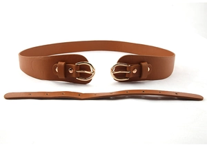 Détail d'une ceinture en cuir marron avec doubles boucles dorées et texture mate lisse