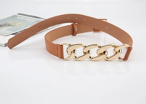 Détail d'une ceinture marron texture crocodile avec boucle à maillons de chaîne dorée