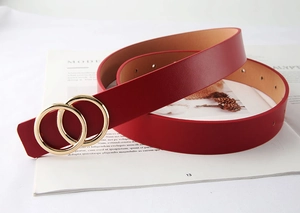 Détail d'une ceinture en cuir rouge avec boucle double anneau doré sur un magazine