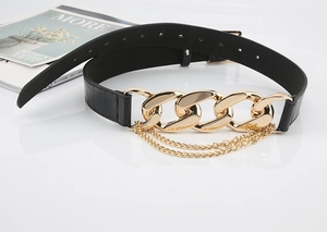 Détail d'une ceinture noire aspect crocodile avec des maillons de chaîne dorés élégants