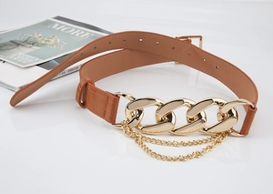 Détail de la ceinture marron en similicuir avec chaîne dorée et franges à glands