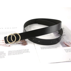 Ceinture classique en cuir noir avec boucle dorée à double anneau sur un magazine