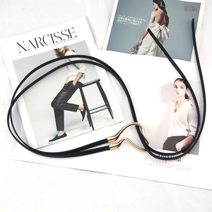Fashionable thin black waist belt with gold heart buckle over lifestyle magazines