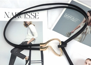 Detail of a thin black leather belt with a golden heart-shaped buckle on a magazine