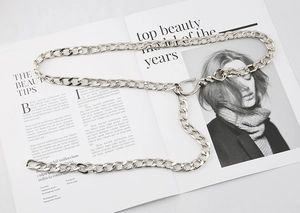 Silver Cuban link metal waist chain for jeans with adjustable J-hook clasp on a magazine background