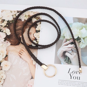 Détail d'une ceinture tressée marron foncé avec une boucle ronde dorée élégante