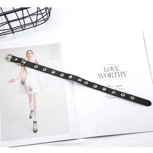 Détail d'un tour de cou en cuir PU noir avec œillets métalliques sur un magazine de mode
