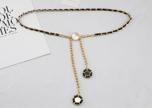 Detailaufnahme der goldenen Metallkette mit schwarzem Leder und Kamelien-Anhängern