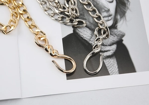 Close-up of heavy gold and silver hip-hop metal chains with large twist hooks for jeans