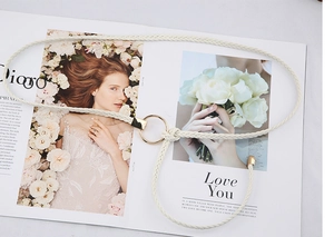 Détail de la ceinture tressée beige avec boucle dorée et finitions en franges
