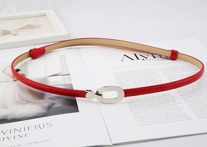Détail d'une ceinture en cuir verni rouge avec boucle argentée sur un magazine de mode