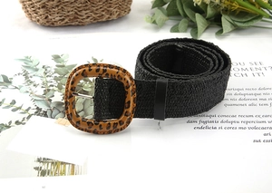 Detail of black woven straw belt featuring a large leopard print square buckle on a magazine