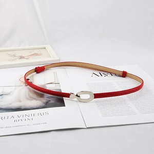 Ceinture fine en cuir rouge avec boucle ovale argentée sur un magazine de mode