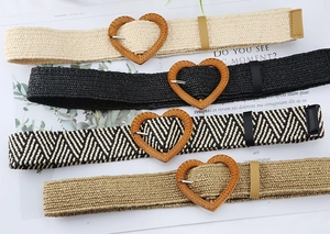 Detail view of woven straw belts with heart-shaped wooden buckles in four natural colors