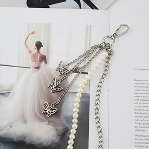 Silver multi-layer waist chain with butterfly pendants and faux pearls on a magazine