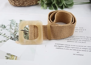 Detail of straw woven belt with bohemian amber resin buckle on a magazine background