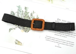 Detail shot of black woven straw belt with square resin buckle and metal pin on white magazine