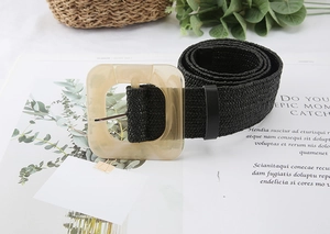 Detail of black woven belt featuring a large square translucent resin buckle on a magazine