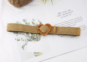 Detail view of woven straw belt featuring a heart-shaped buckle on an open magazine background