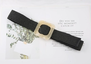 Detailed view of black woven straw belt featuring a large square acrylic buckle on magazine