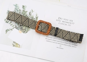 Detail of bohemian straw woven belt with geometric chevron pattern and square buckle