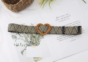 Detail of woven straw belt with heart-shaped buckle on a lifestyle background
