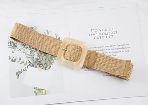 Close-up of a woven straw belt with a square resin buckle on a magazine page