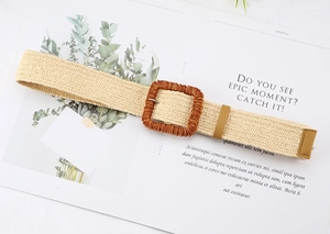 Detail of bohemian straw woven belt featuring a textured square buckle and leather ends
