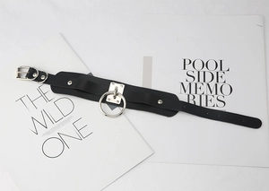 Detail of a punk style black PU leather choker featuring a large silver metal ring and rivets