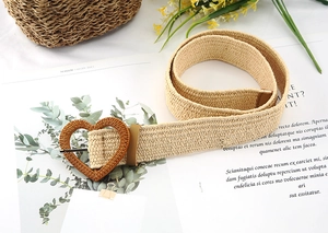 Detail of bohemian straw woven belt featuring a textured heart-shaped buckle and pin buckle