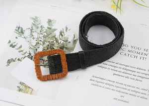 Detailed macro view of black woven straw belt with orange-brown square buckle on magazine
