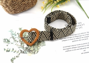 Close-up of woven straw belt with heart-shaped buckle and zigzag pattern details