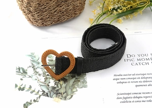 Close-up of black woven belt featuring a heart-shaped buckle in straw texture