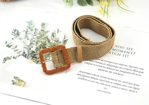 Macro shot of khaki straw woven belt featuring a large square buckle and natural texture