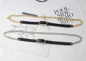 Dettagli di cinture in ecopelle nera con eleganti catene in oro e argento fini
