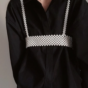 Exquisite white pearl body chain with woven beaded strap design over a black shirt detail