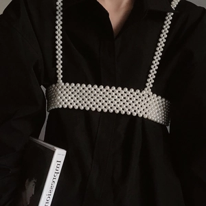 Detail shot of the handcrafted white pearl woven body chain over a black shirt