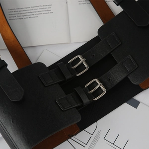 Détail d'une large ceinture corset punk noire avec doubles boucles argentées sur magazine